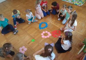dzieci siedzą w kole i układają wzory z kolorowych kropek