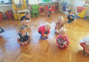 dzieci bawią się kucając w obręczach