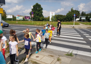 dzieci parami przechodzą po pasach