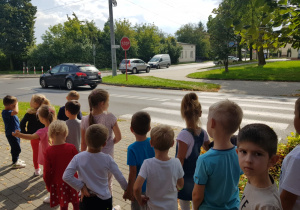 dzieci stoją przy skrzyżowaniu dróg i oglądają znak - stop