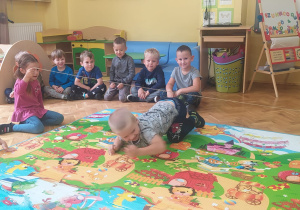 zawody chłopców - chłopiec czworakuje pod liną trzymaną przez dziewczynki