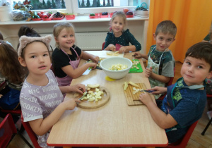 dzieci w fartuszkach kroją gruszki na tackach