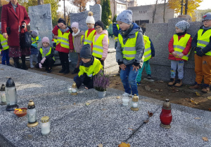 dzieci kładą znicze pod pomnikiem nieznanego żołnierza