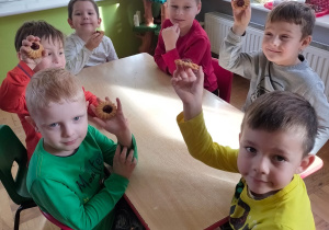 chłopcy przy stoliku pokazują jakie ciastko kupili w piekarni