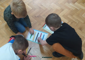 dzieci na podłodze układają kredki według wzoru