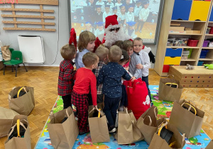dzieci tulą się do Mikołaja, który siedzi wśród nich