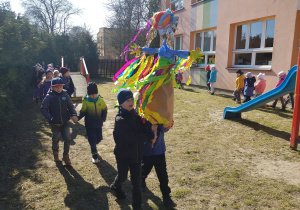 korowód dzieci z Marzanną wokół budynku przedszkola w ogrodzie