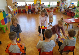 zabawa - dziewczynki niosą talerzyki z owocami w jak najszybszym tempie w kierunku chłopców siedzących na krzesełkach