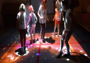 ciemno, dzieci chodzą po macie w świetle, w kształcie gwiazd z FUN FLOOR