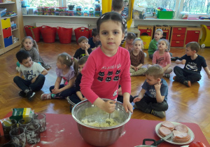 dziewczynka miesza łyżką ciasto na pizzę w dużej, srebrnej, metalowejmisce