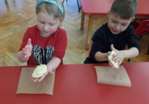 dzieci ugniatają kawałki ciasta na pizzę
