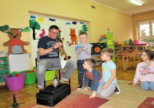 tata gra na trąbce a chłopcy są blisko niego