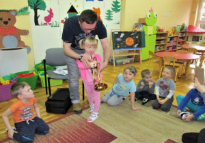 tata uczy dziewczynkę jak trzymać trąbkę