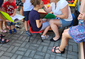 dzieci oczekują w kolejce do malowania twarzy na tarasie przedszkolnym