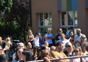 rodzice w ogrodzie przedszkolnym obserwują występy swoich dzieci