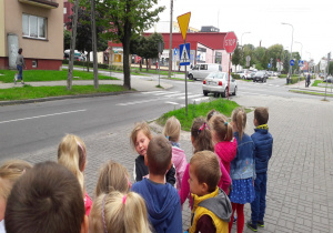 dzieci stoją przy ulicy i obserwują znaki drogowe