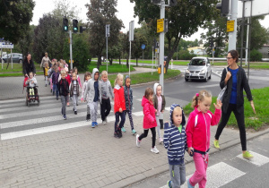 dzieci sprawnie przechodzą przez pasy z nauczycielką a druga prowadzi wózek z dziewczynką