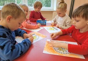 dzieci kolorują flagi z logo przedszkola - słoneczkiem