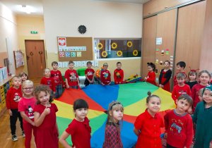 dzieci ubrane na czerwono pozują do zdjęcia z kolorową chustą animacyjną