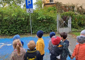 dzieci stoją przed znakiem i miejscem do parkowania dla niepełnosprawnych