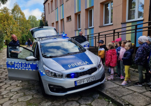 przedszkolaki stoją przed przedszkolem przy radiowozie