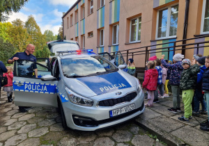 dzieci przed przedszkolem oglądają radiowóz w obecności palicjantów