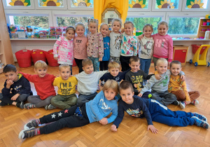 dzieci z grupy VI pozują do zdjęcia, dziewczynki stoją a chłopcy siedzą i leżą przed nimi