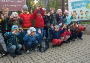 dzieci przed wejściem do przedszkola z zebranymi śmieciami