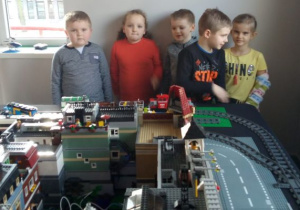 dzieci oglądają miasteczko zbudowane z klocków Lego: tory, domy, dźwigi