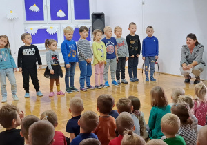 dzieci śpiewają piosenkę a obok kuca nauczycielka