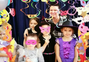dziewczynki z opiekunką wśród balonów i serpentyn z przyłożonymi maskami do twarzy