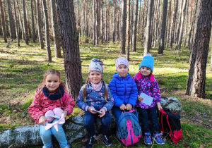 w lesie - dziewczynki siedzą na zwalonym pniu drzewa