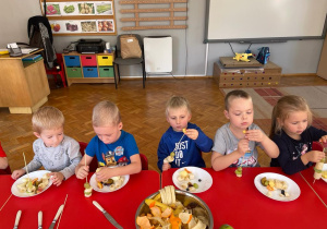 dzieci nakładają na szaszłykowe patyki owoce