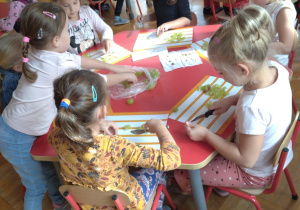 dzieci kroją winogrona na tackach przy stoliku, na sałatkę owocową
