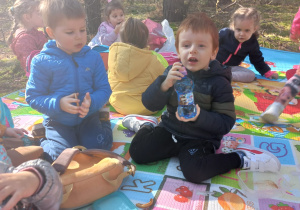 dzieci siedzą na kolorowych matach w lesie