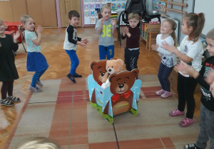 dzieci tańczą i klaszczą wokół wagonika z misiami