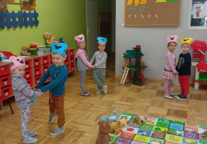 przedszkolaki tańczą w parach w okolorowych paskach misiów na głowie