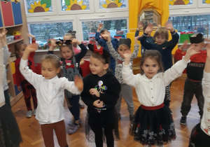 przedszkolaki tańczą z rękami uniesionymi w górze