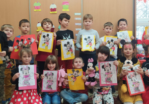 pzredszkolaki z grupy III pozują do zdjęcia grupowego z kartkami z naklejonymi puzzlami Myszki Miki