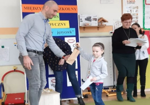 dziewczynka w szarej marynarce odbiera nagrodę