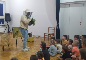 prtzedszkolaki słuchają wykładu pszczelarza, który trzyma słoneczniki