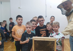chłopcy z pszczelarzem stoją przy okienku z pszczołami