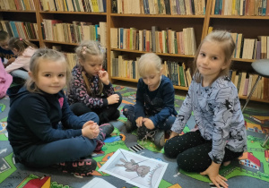 w bibliotece - dziewczynki siedzą wokół ułożonych puzzli z misiem