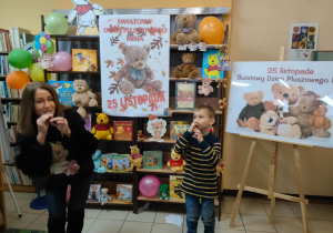 w bibliotece - pani bibliotekarka i chłopiec demostrują jak gra się na trąbce