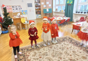 dziewczynki w czerwonych ubraniach stoją w kole i śpiewają piosenkę