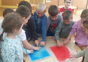 dzieci dotykają kolorowy śnieg