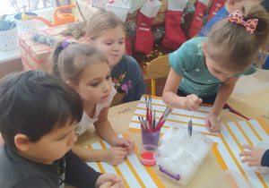 dzieci nakładają śnieg łyżkami do pojemników