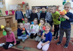 dziewczynki trzymają tulipany z papieru a chłopcy stoją za nimi