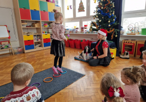 dziewczynka idzie na palcach po ułożonych obręczach zanim dojdzie do psa