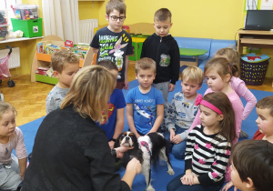 dzieci zgromadzone wokół psa Molly słuchają wiadomości podawanych przez jego opiekunkę